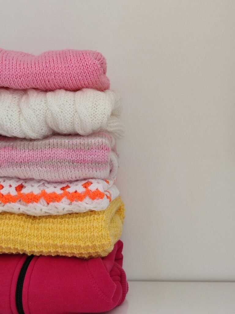 Folded merino sweaters in cream, ochre, and stone